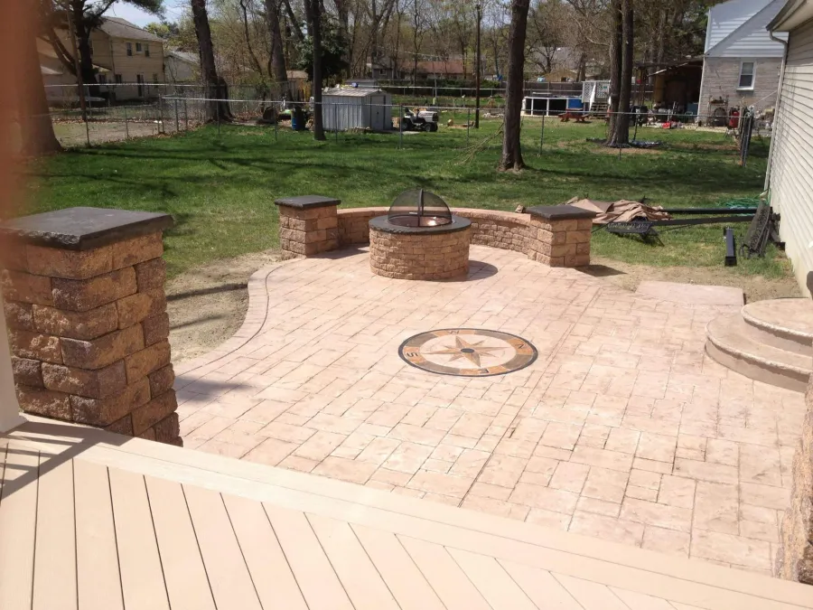 new brown composite deck stamped concrete patio fire pit