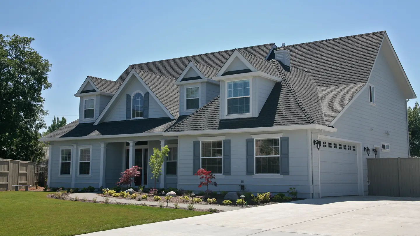 A white house with a lot of windows and black shingles on the roof in Sicklerville, NJ