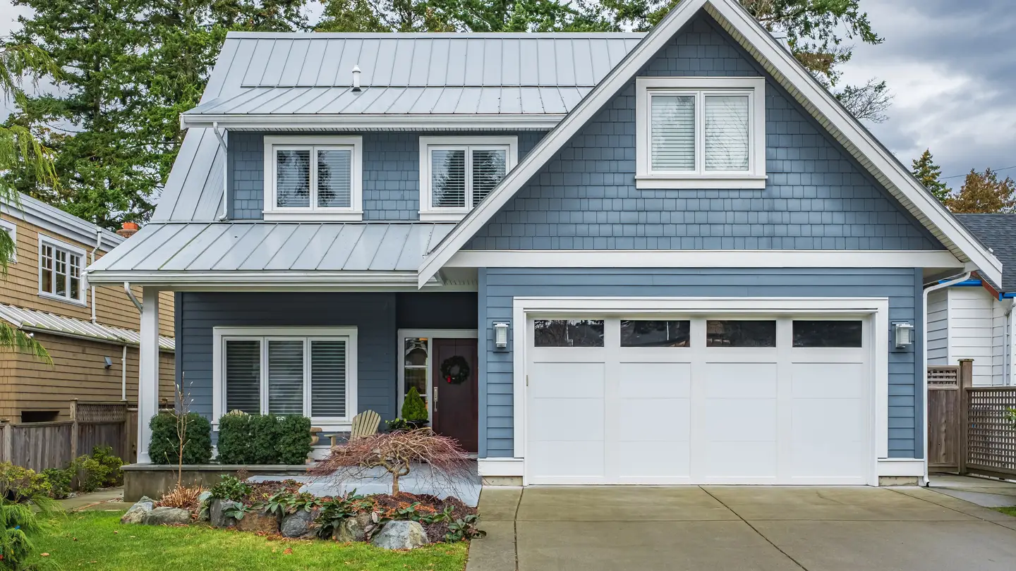 A home with blue siding, white trim, and blue metal roofing