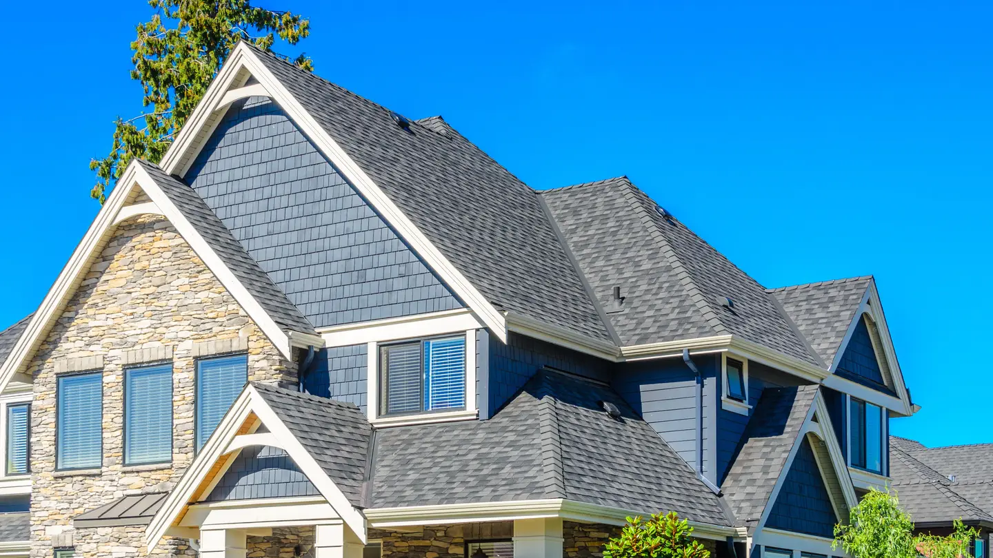 A large house with different levels of rooftops and multiple windows.
