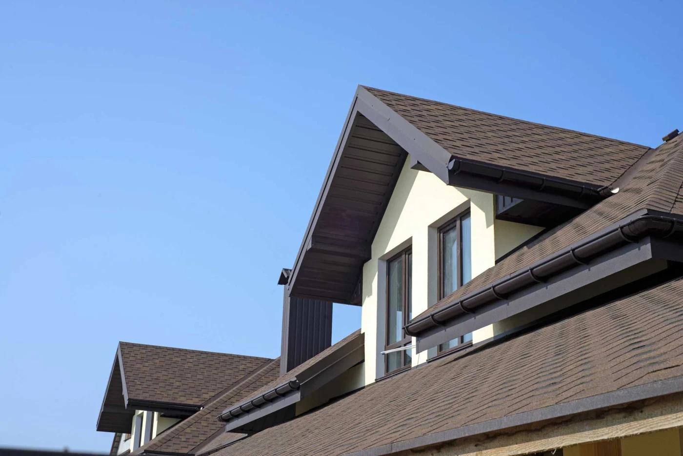 A tan-colored home with a recently replaced brown roof