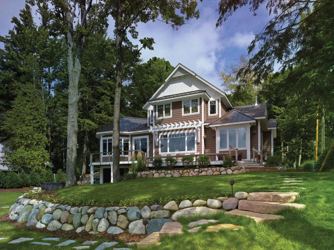 Brown house with large windows, white trim, and stone landscaping