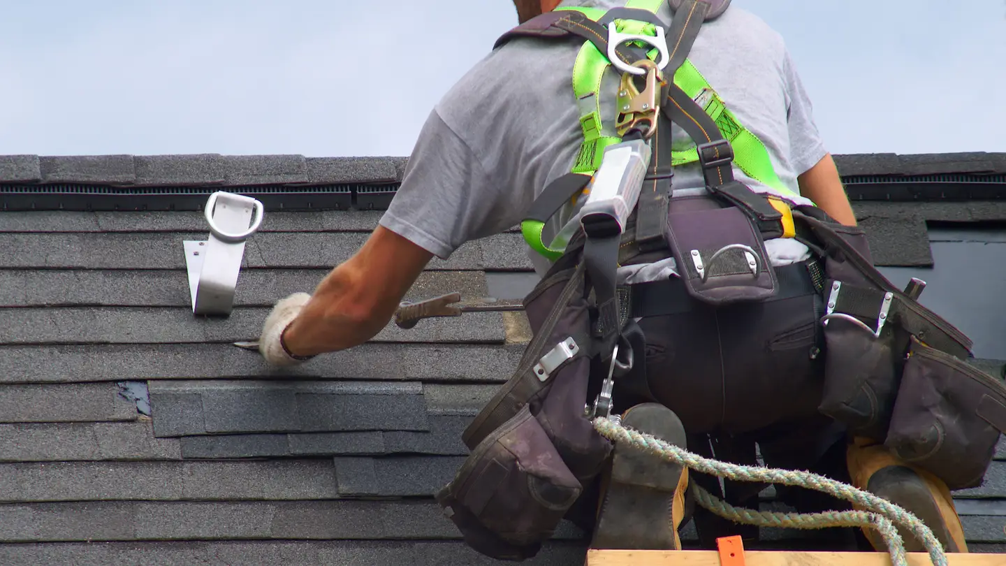 A worker with safety gear on installing roofing shingles in Marlton, NJ, by Ameritech Services.