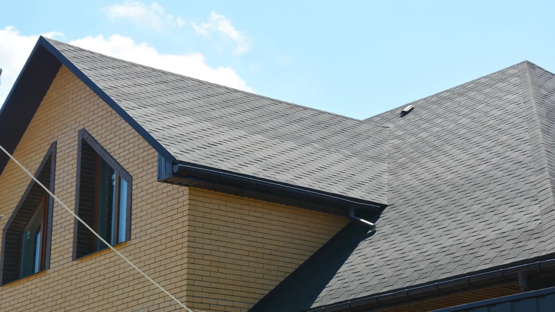 A house with yellow brick and two windows on the roof with black shingles in Deptford, NJ by Ameritech Services