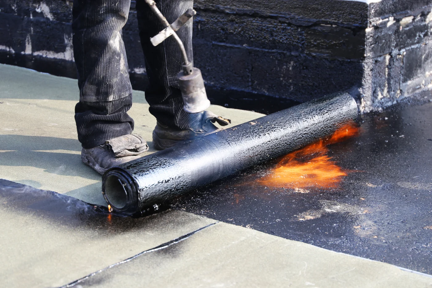 An Ameritech NJ roofer is waterproofing a flat roof with bitumen membranes.