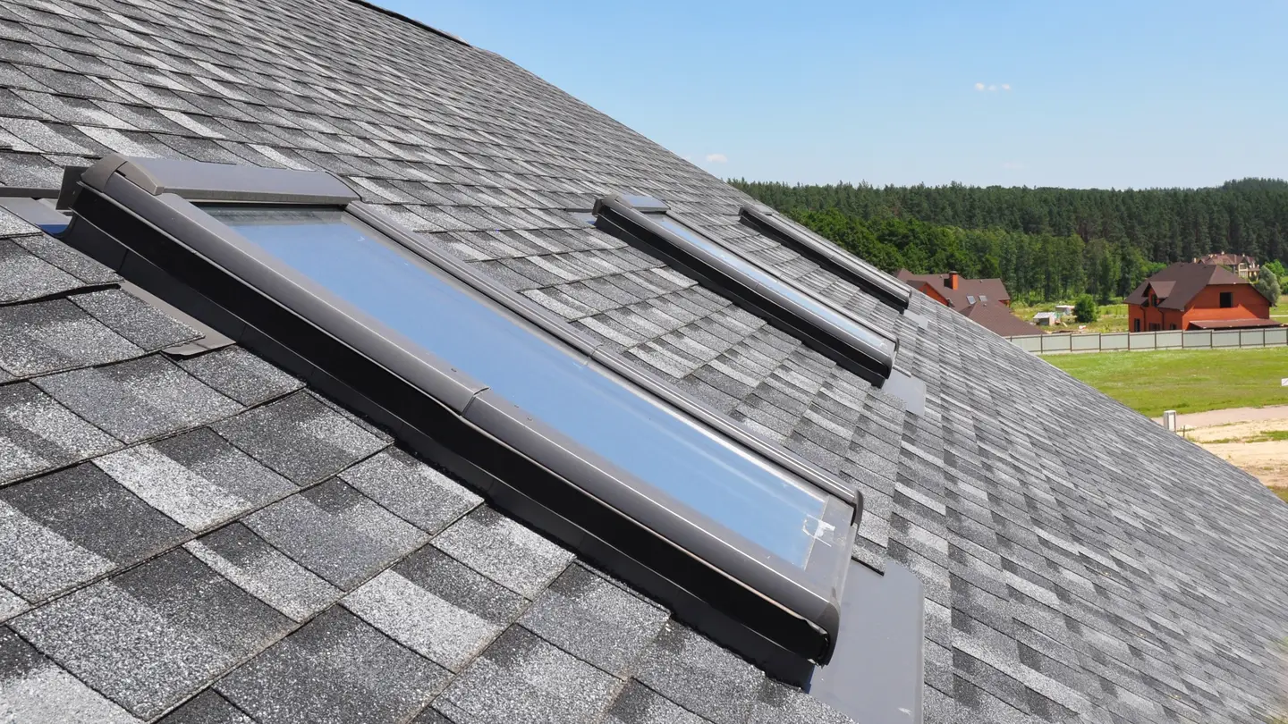A closeup of a roof with grey shingles and three skylights in Cherry Hill, NJ, by Ameritech Services