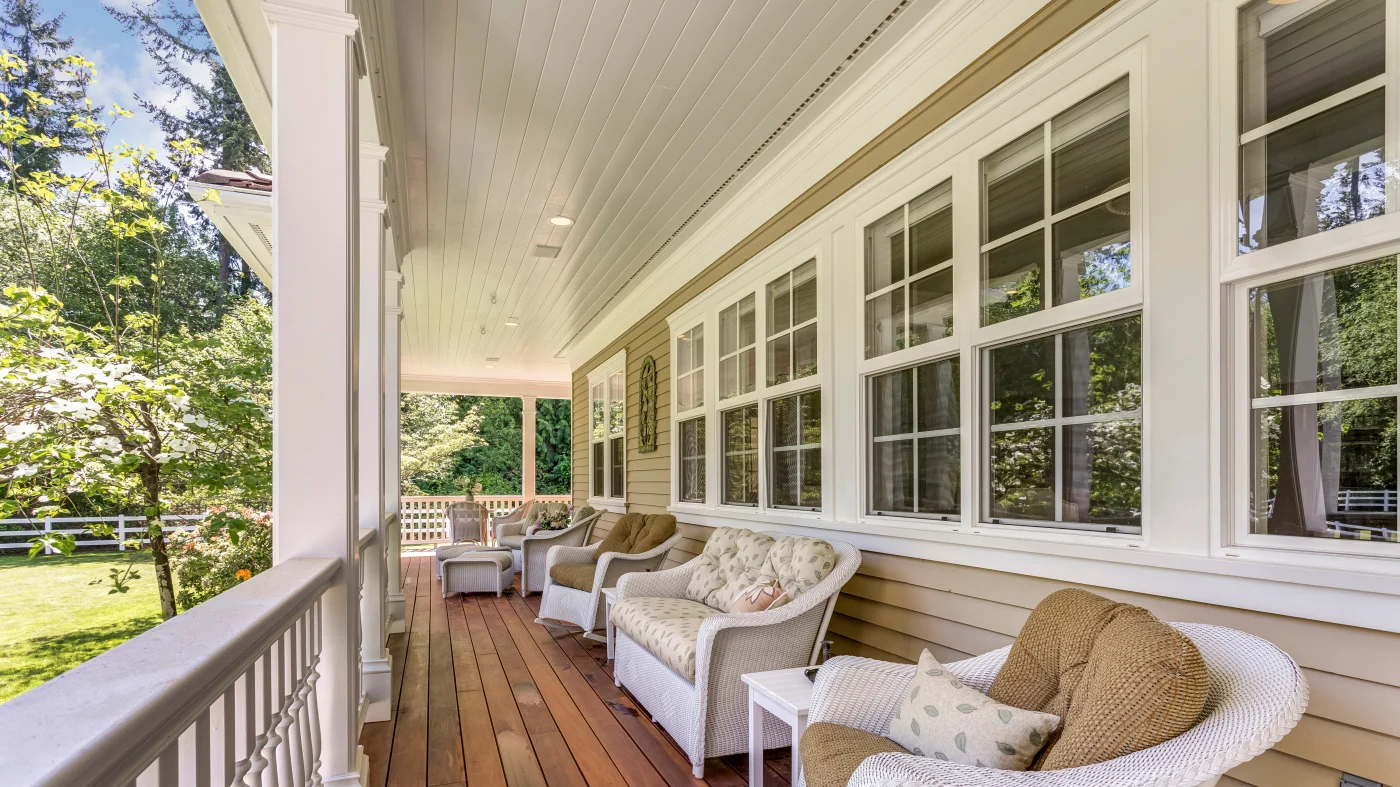A row of double-hung windows along a front porch with several outdoor seats