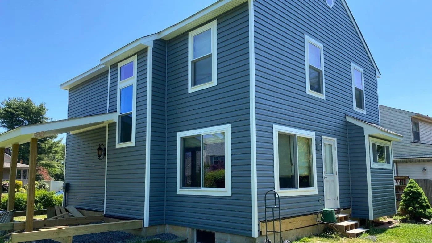 A blue-sided home with several newly installed replacement windows
