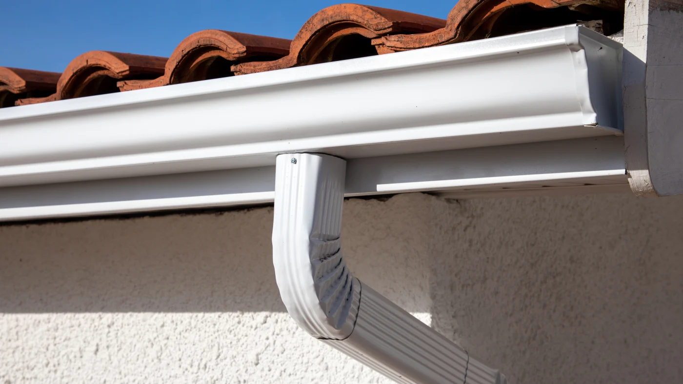 Closeup of a white gutter and the top of a downspout