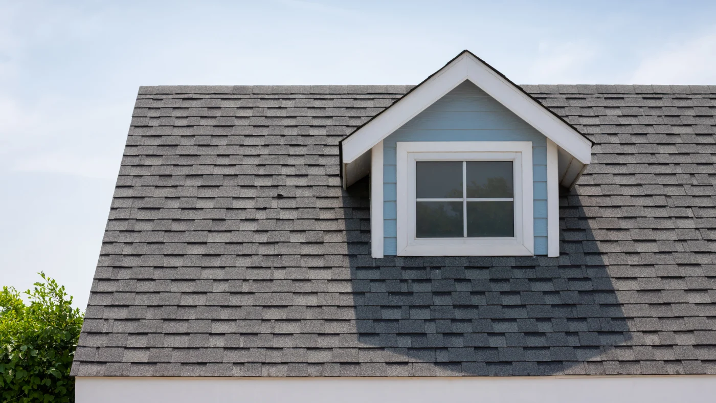 A gray asphalt shingle roof with a dormer window
