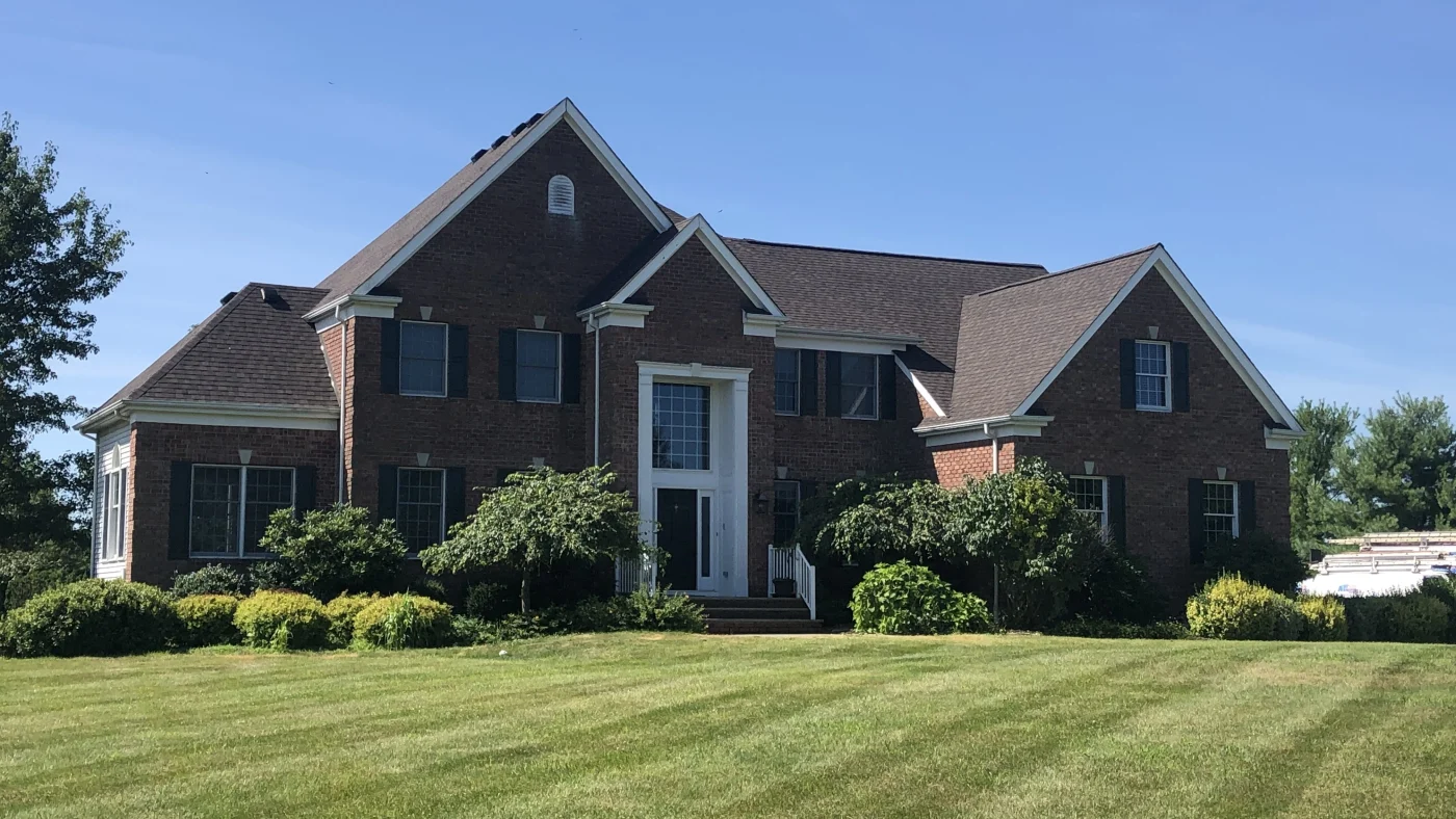 A large brick home with a brown shingle roof
