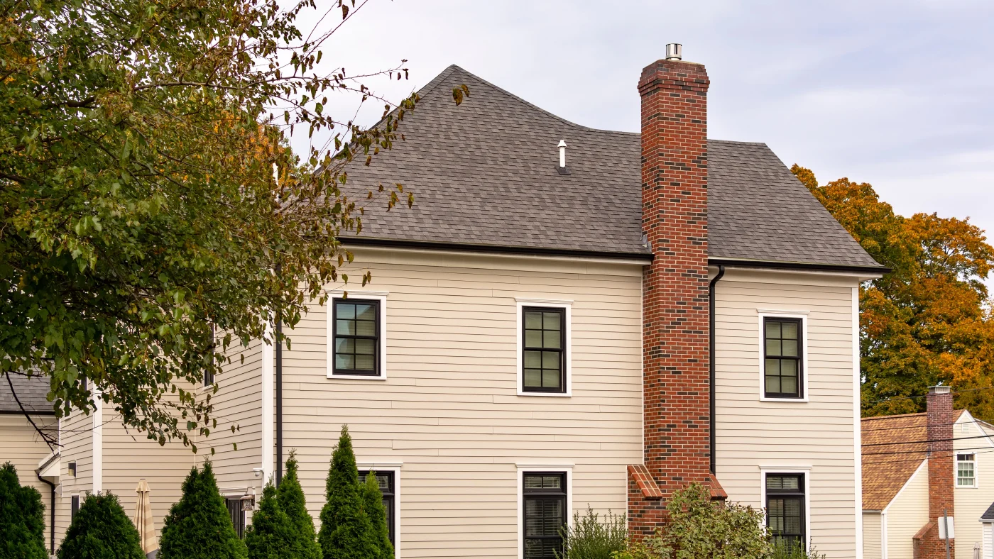 A cream-colored home with gray asphalt shingle roofing