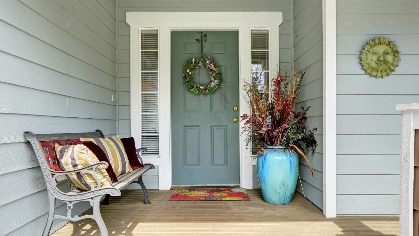 A light green entry door with sidelights and a wreath