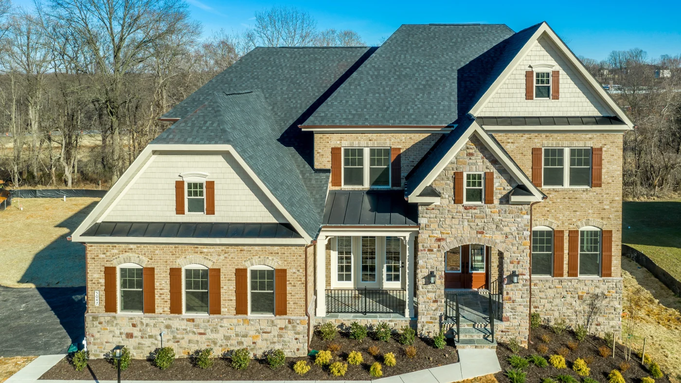 A large home with stone siding and a gray asphalt shingle roof