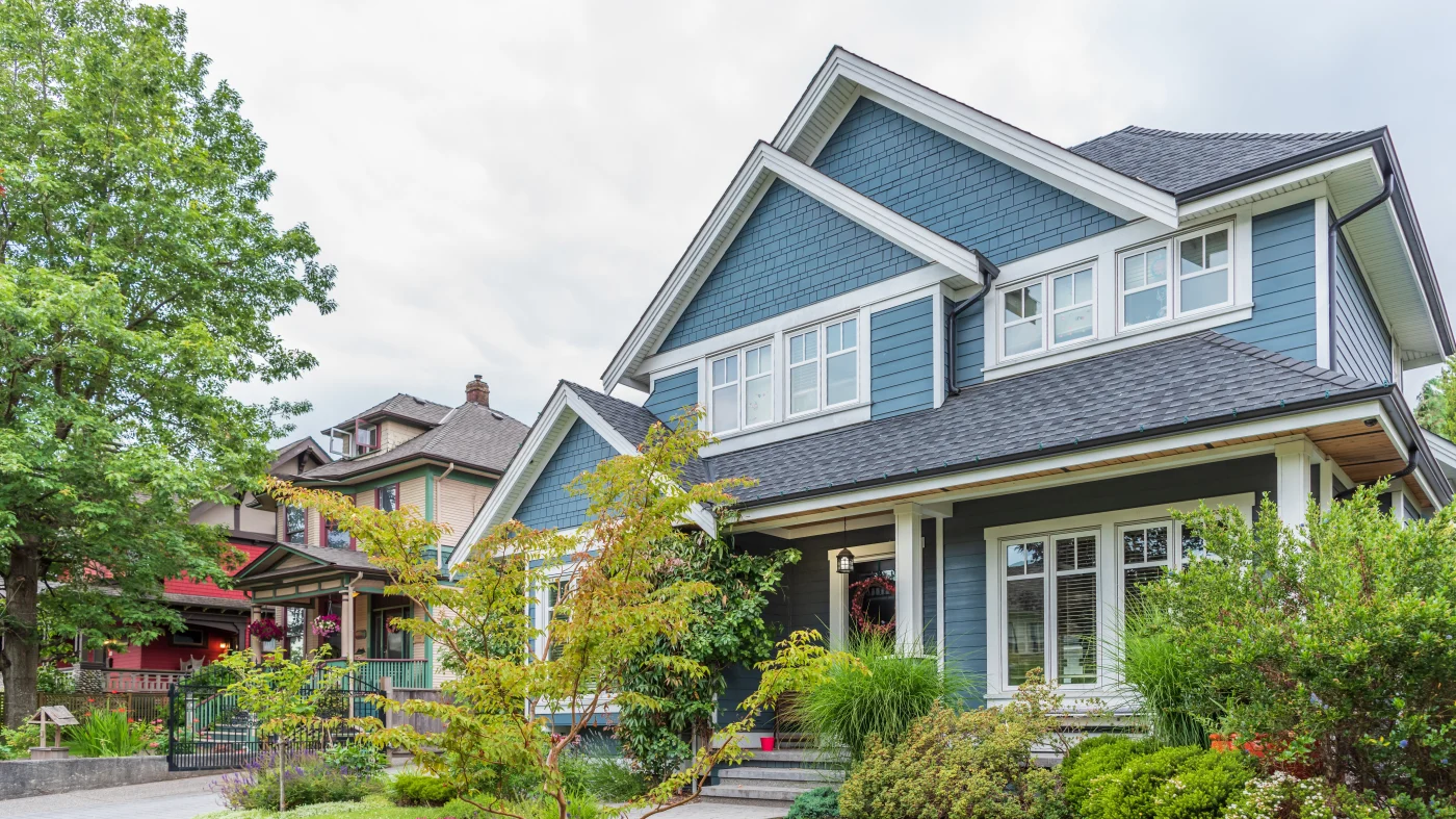 A two-story blue-sided house with white trim and a gray asphalt shingle roof