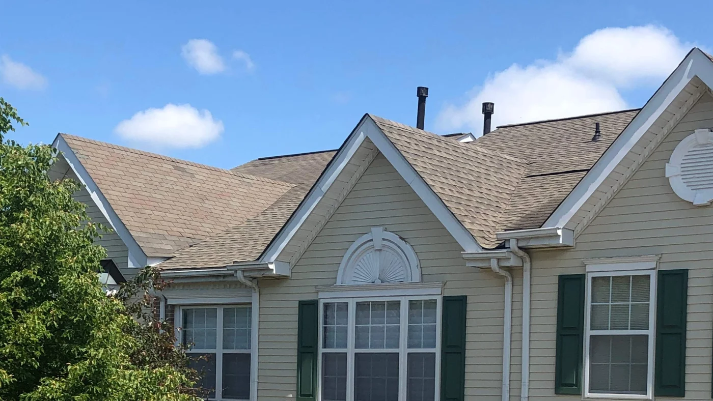 A tan-sided home with brown asphalt shingles