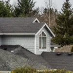 A blue multi-story house with gray asphalt shingle roofing