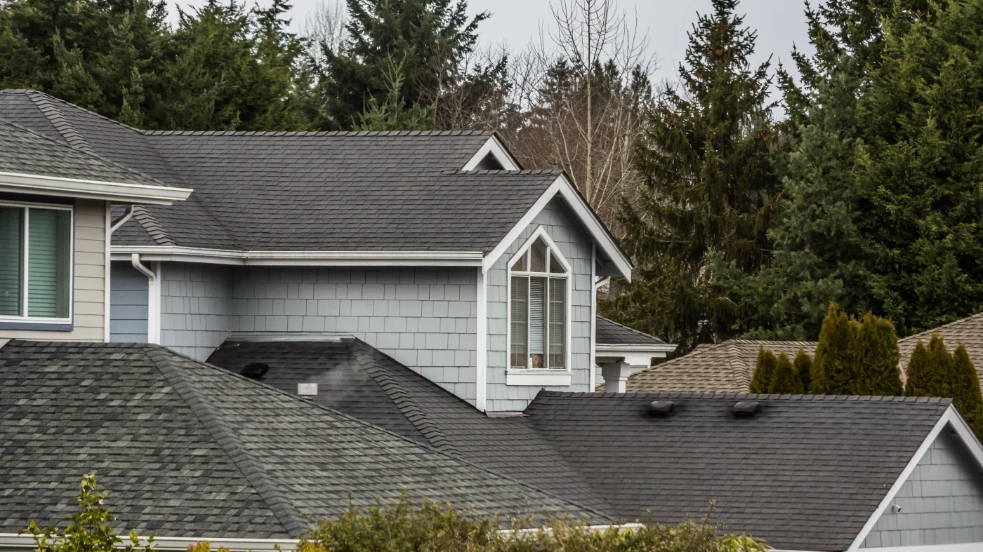 A blue multi-story house with gray asphalt shingle roofing