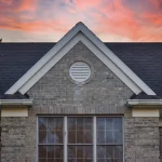 Home with stone siding and a black asphalt shingle roof