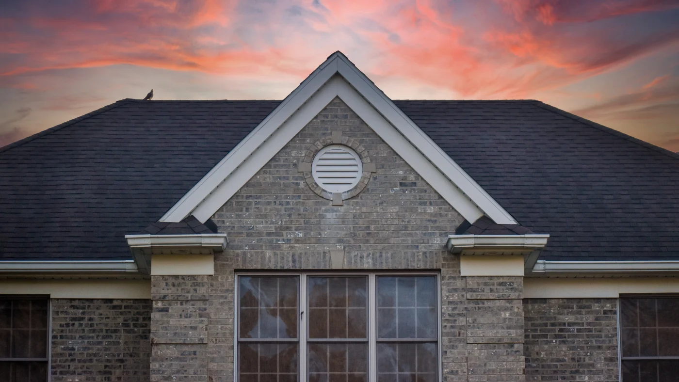 Home with stone siding and a black asphalt shingle roof