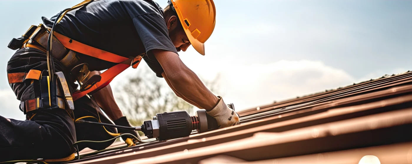 Roofer in orange hard hat installing roof shingles