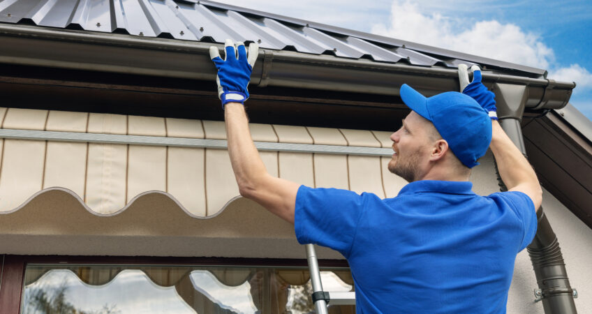 A Roofing Contractor Installs Gutters And Gutter Guards On A House