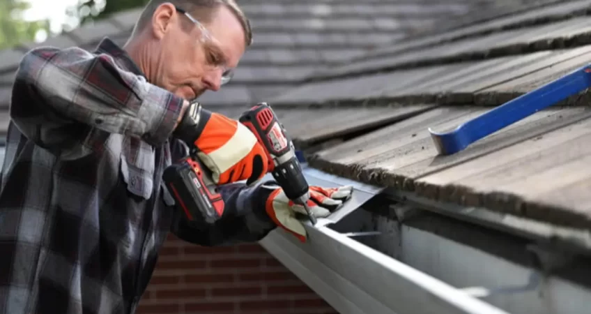 A man installing gutter guards in a home with a brown roof